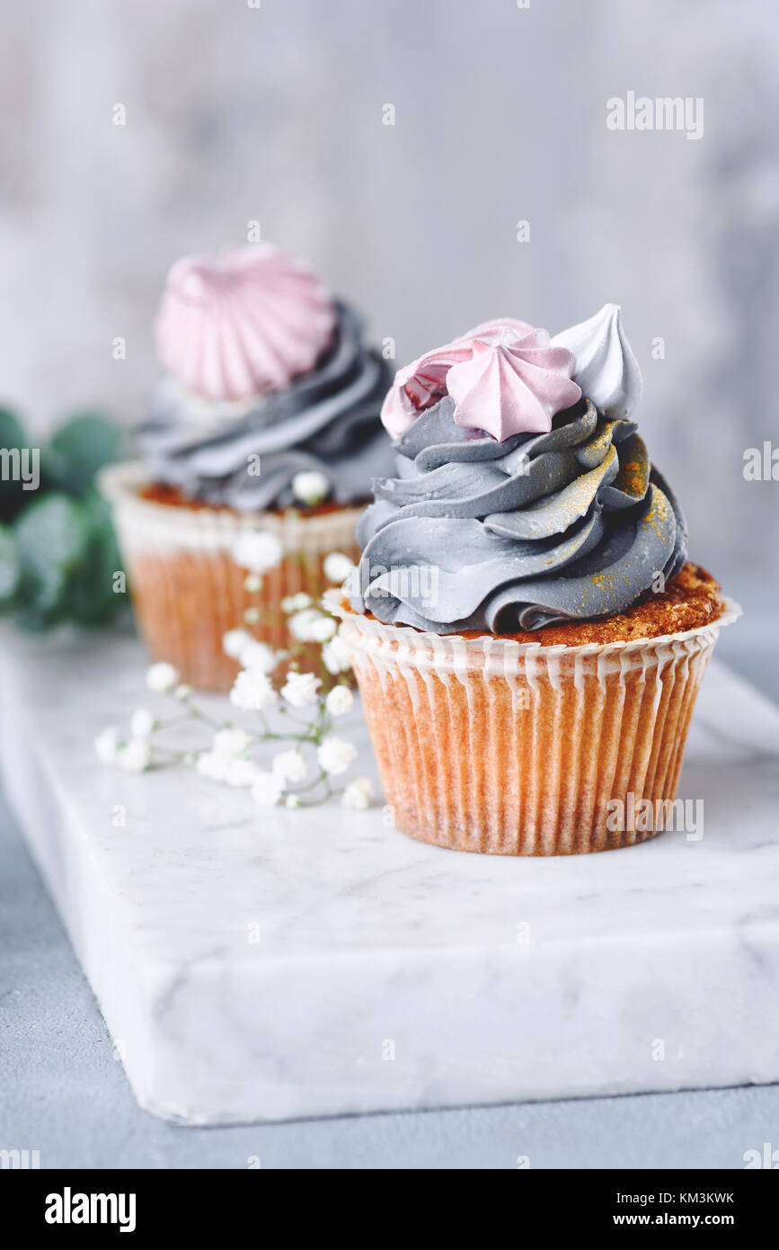 Cupcakes mit grauen buttercream Frosting und Baiser Küsse auf Marmor. Detailansicht. Hochzeitstorten Stockfoto