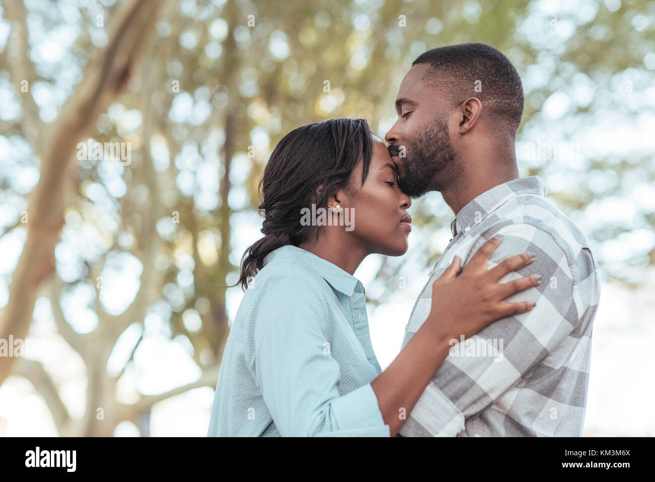 Romantische junge afrikanische Mann küssen Stirn draußen seiner Freundin Stockfoto