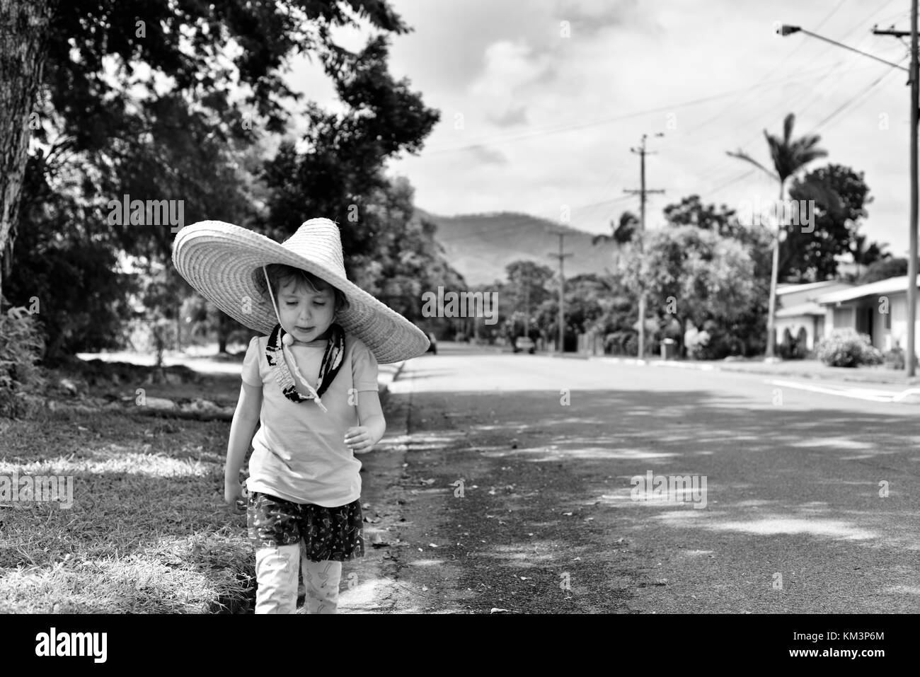 Junge Mädchen mit einem Sombrero zu Fuß in einer Vorstadtstraße, Townsville, Queensland, Australien Stockfoto