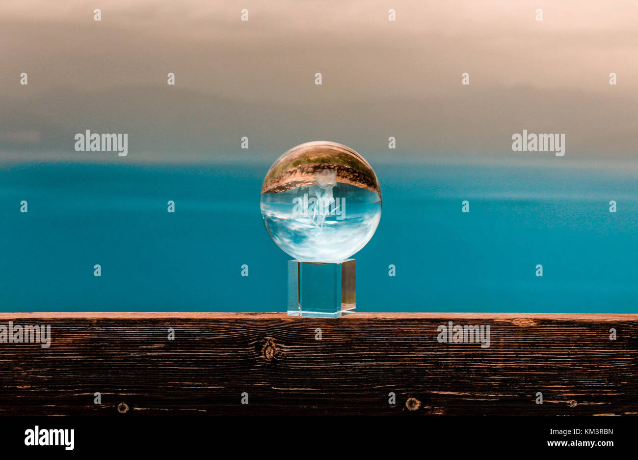 Crystal Ball auf einer Bank am Rande einer Klippe mit bunten Landschaft im Hintergrund das Meer und die Wolken Griechenland Dezember Stockfoto