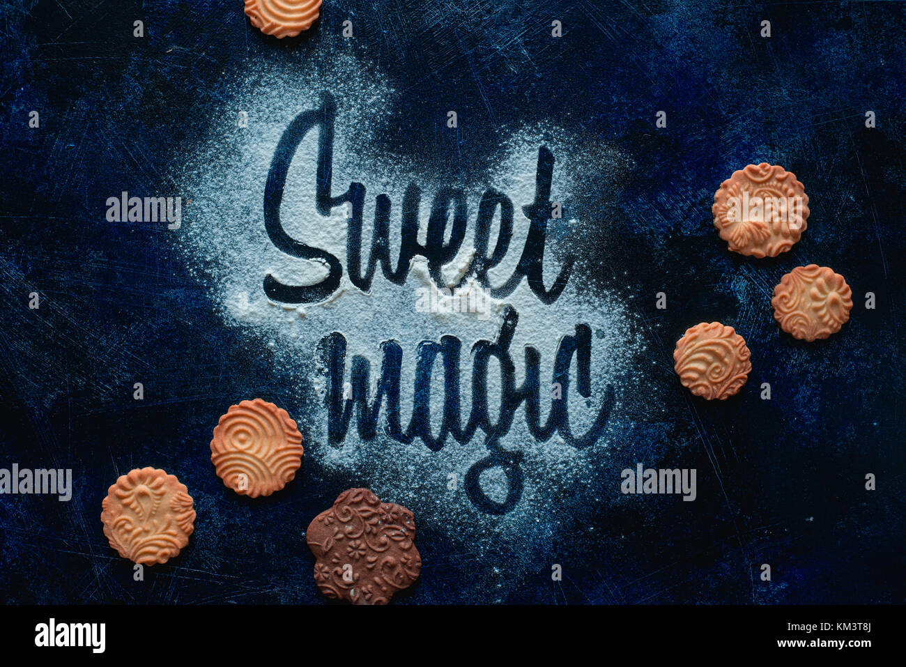 Worte Sweet Magic mit Mehl. Cookies und Zucker Pulver auf einem dunklen Hintergrund. Essen Typografie Konzept. Süße flach. Stockfoto