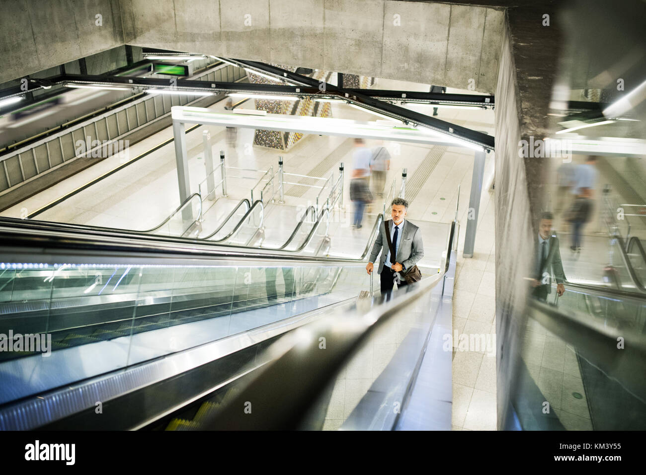 Geschäftsmann auf einer Rolltreppe auf einem U-Bahnhof entfernt. Stockfoto