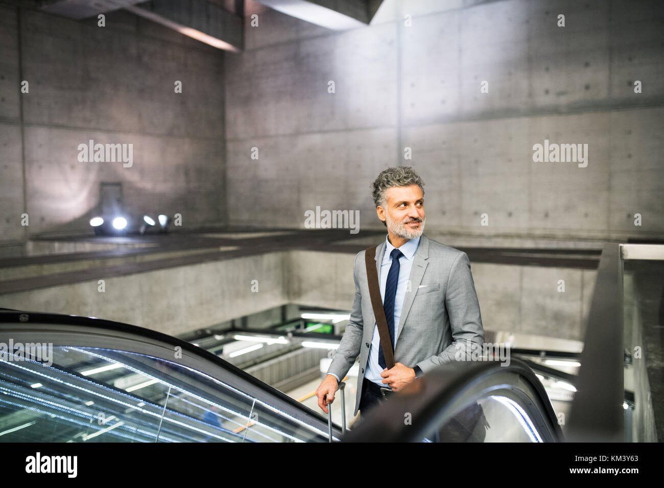 Geschäftsmann auf einer Rolltreppe auf einem U-Bahnhof entfernt. Stockfoto