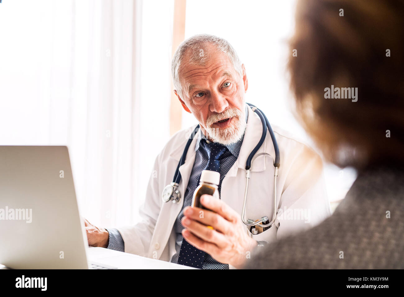 Arzt mit Laptop im Gespräch mit einer älteren Frau im Amt. Stockfoto Arzt mit Laptop im Gespräch mit einer älteren Frau im Amt. Stockfoto