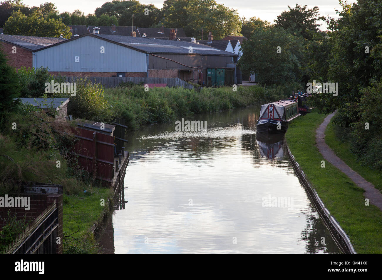 Narrowboats günstig für die Nacht mit industriellen Gebäude entlang auf dem Coventry Canal in der Nähe von Tamworth, Staffordshire, England. Stockfoto