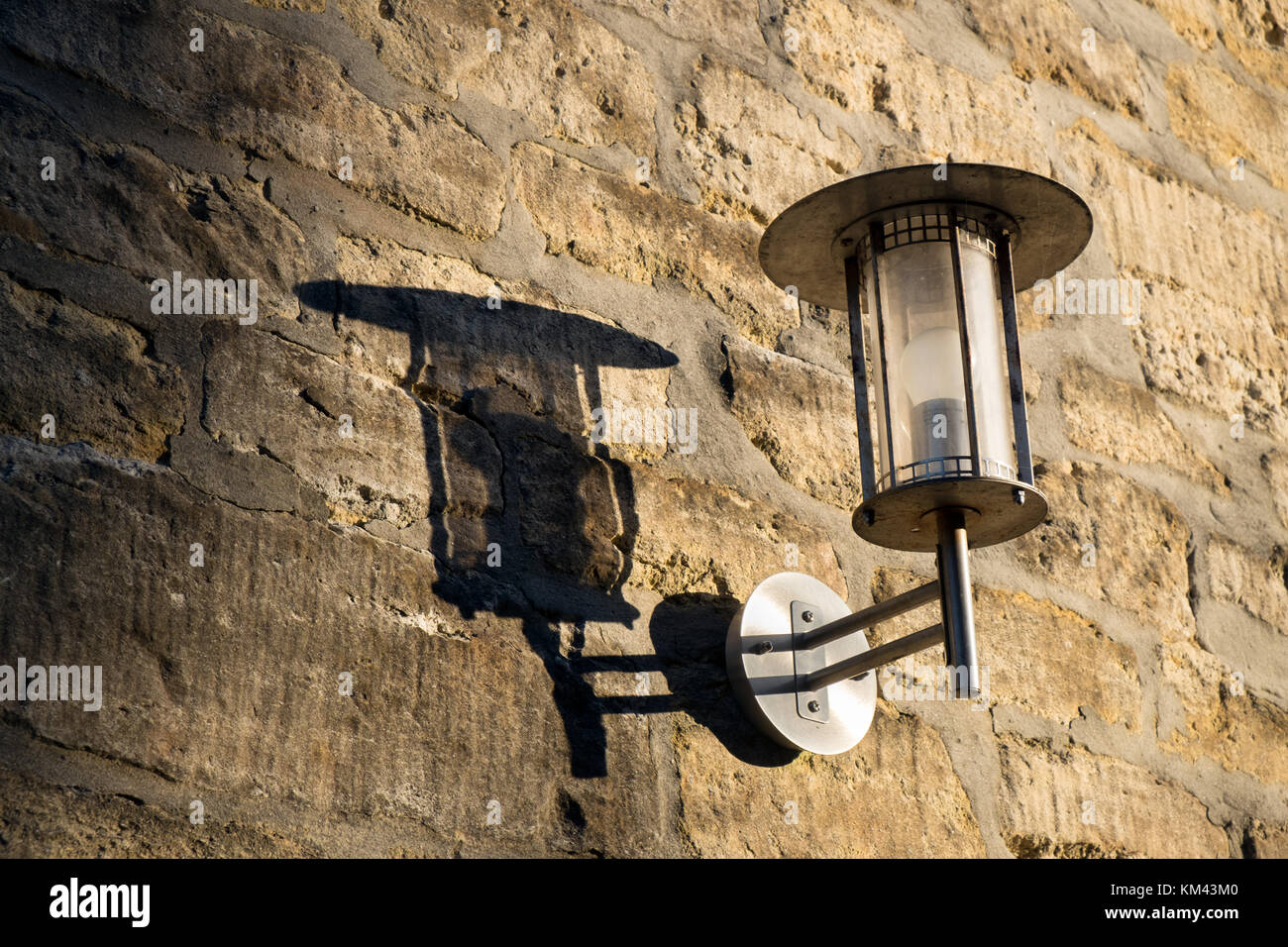 Eine Laterne, auf einer Steinmauer. Casting eine harte Schatten im hellen Sonnenschein Stockfoto