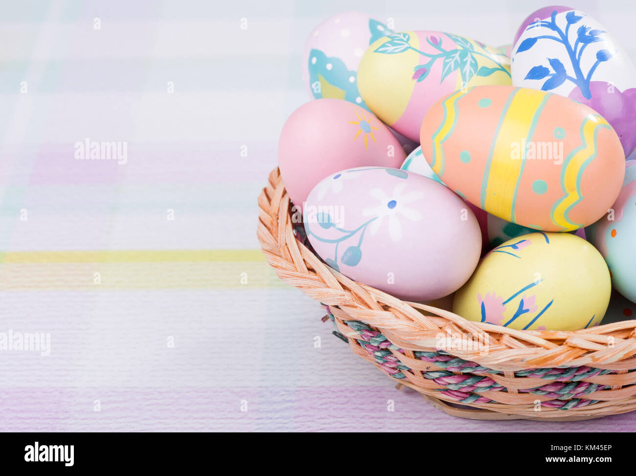 Korb mit bunten Ostereier auf einer pastellfarbenen Oberfläche Stockfoto