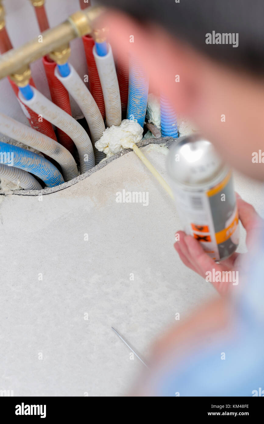 Klempner spritzen Schaum um Rohre Stockfoto