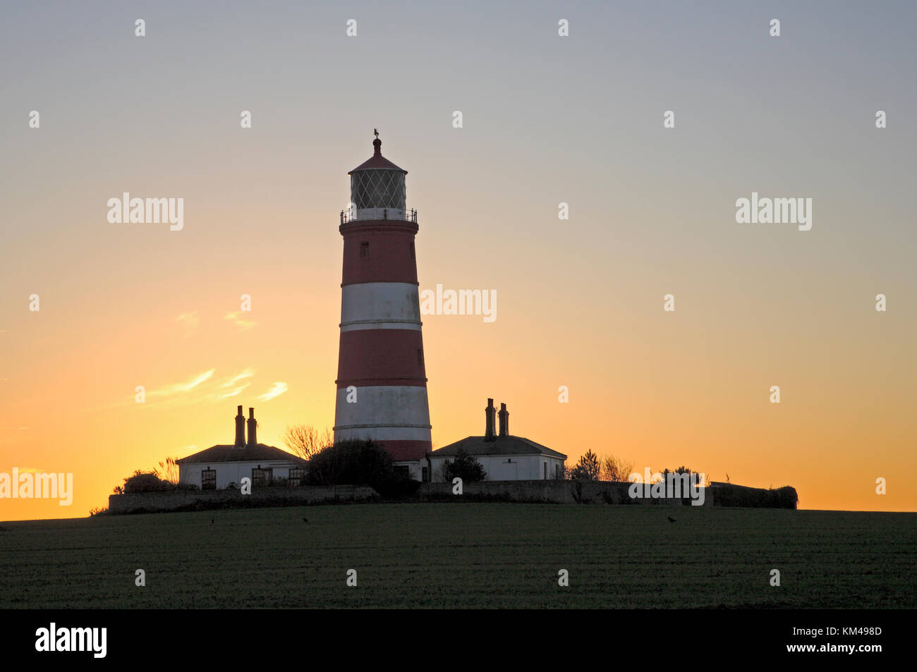 Ein Blick auf den Sonnenuntergang hinter dem Hasbro' Lighthouse an der Küste von Norfolk in Happisburgh, Norfolk, England, Großbritannien. Stockfoto