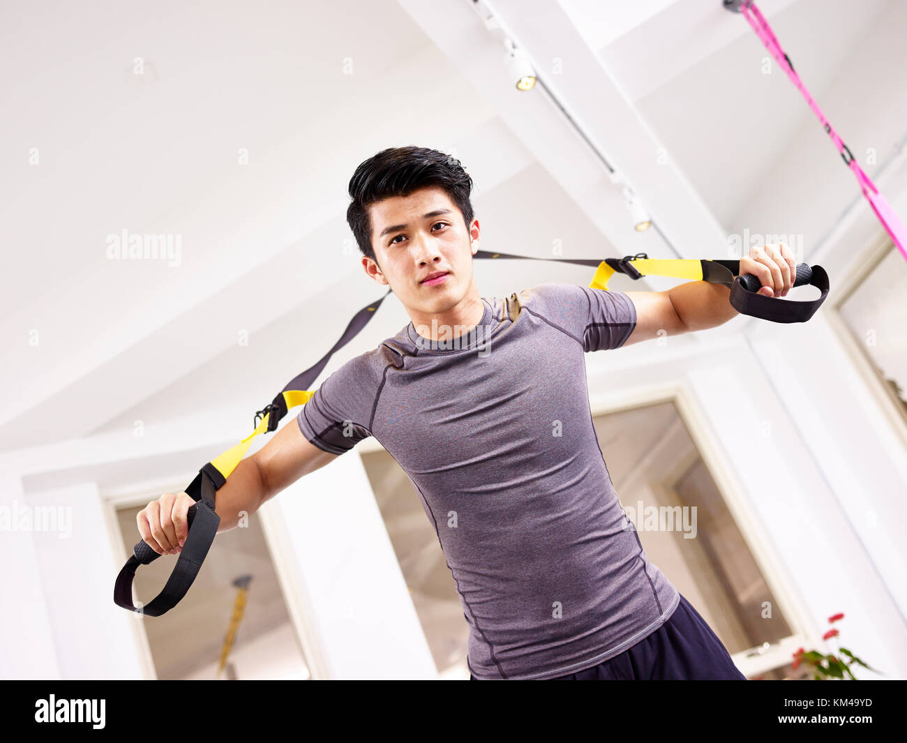 Junge asiatischer Mann das Trainieren im Fitnessstudio mit Fitness-Trägern. Stockfoto