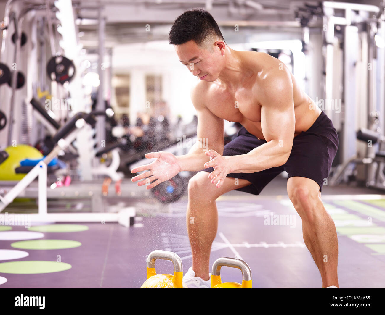 Asiatische männlichen Bodybuilder trainieren Sie im Fitnessraum mit Wasserkocher Glocken. Stockfoto