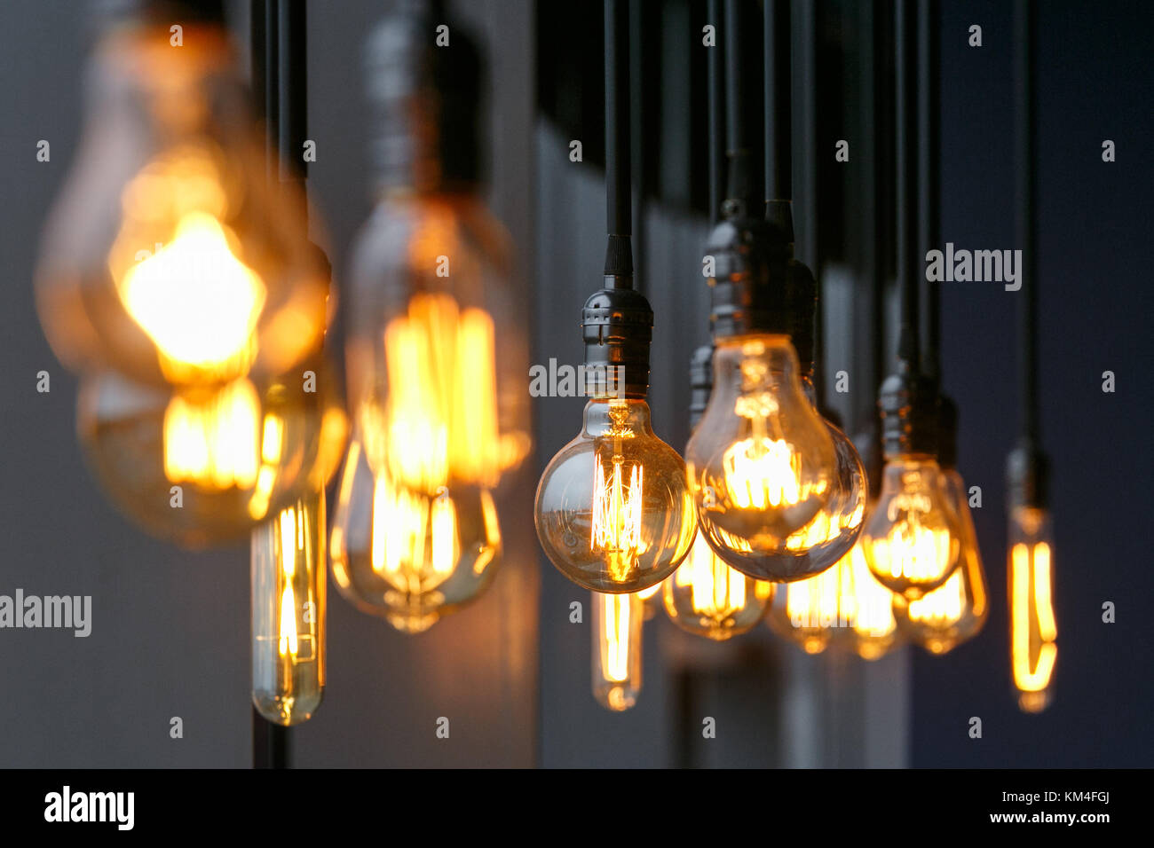 Vintage Wolframwendel mehrere Lampen unterschiedlicher Größe und Stil, die von der Decke hängen auf einem schwarzen Kabel als Interior Design Konzept. Die Energie ein Stockfotografie