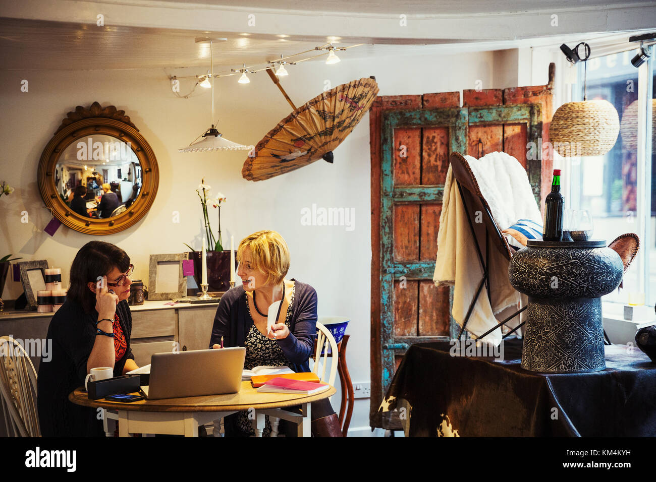 Zwei Frauen in einem kleinen Ladengeschäft sitzt, erscheint ein Pop-up-store, zeigt der Retro und gefundene Gegenstände, upcycled und renoviert. Stockfoto