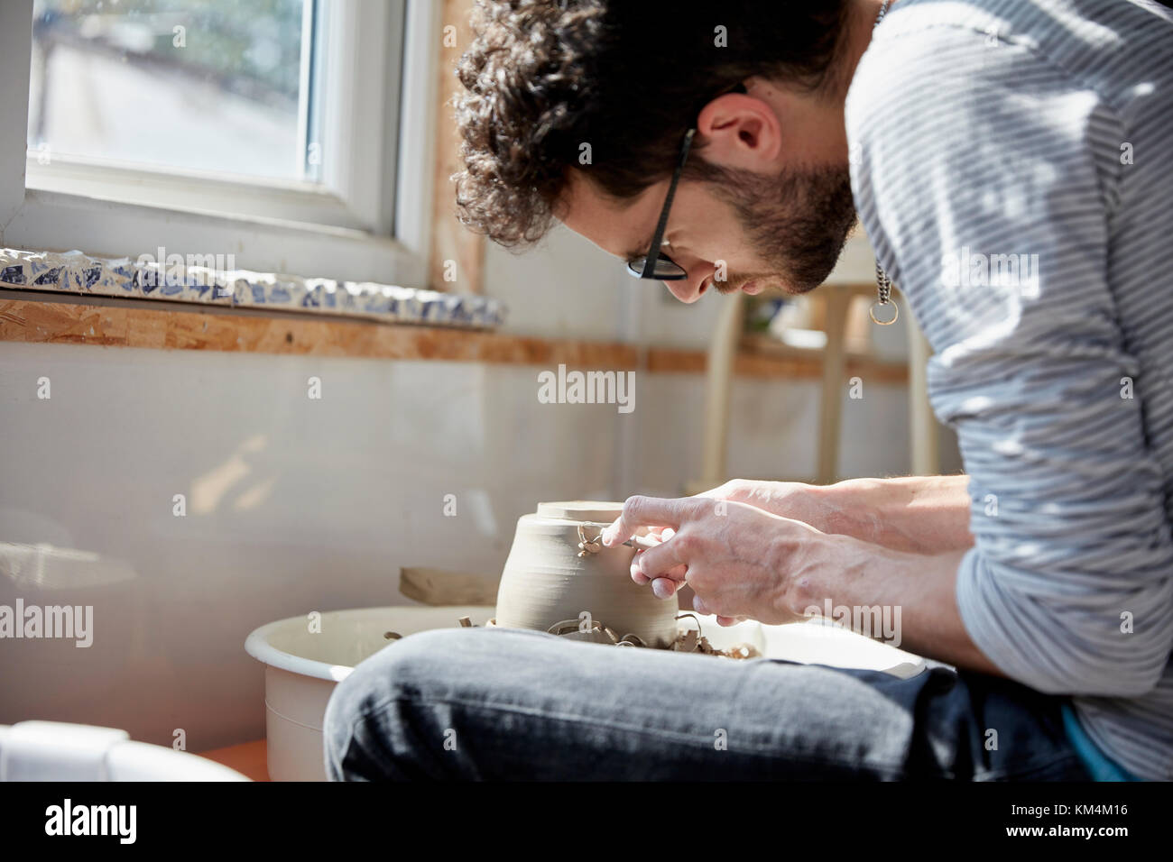 Mann an der Töpferscheibe sitzen, Formen der feuchten Lehm auf den drehenden Plattenteller, in einer Töpferwerkstatt Stockfoto