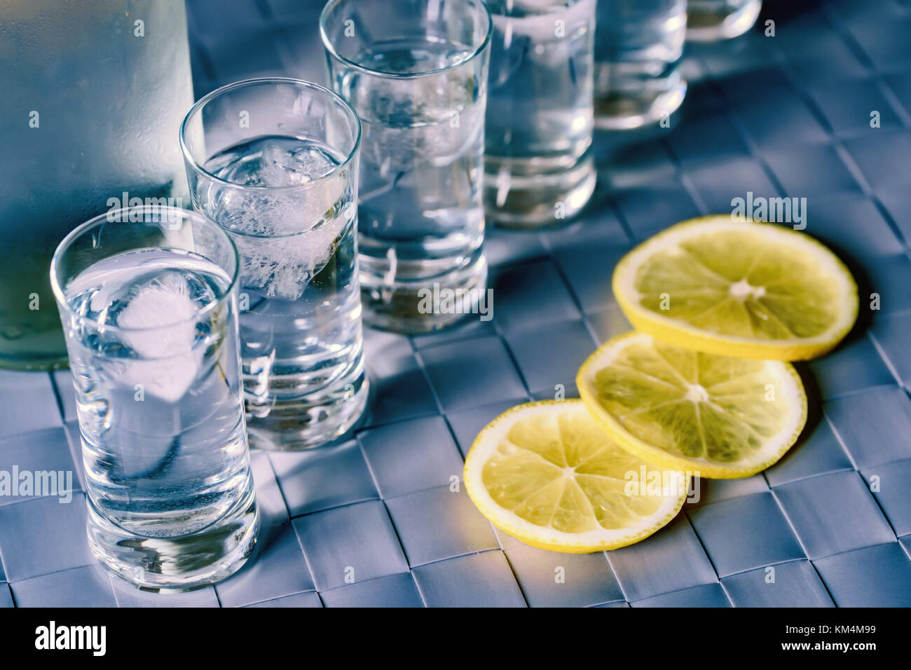 Vodka Shot Glas und Zitrone auf blaue Fläche Stockfoto