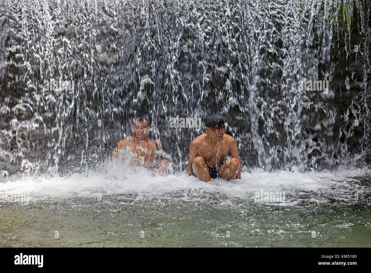 Zwei indonesische Jungen, die in den Benang Kelambu Wasserfällen an den Hängen des Rinjani Vulkans, Zentral Lombok, Indonesien, baden Stockfoto