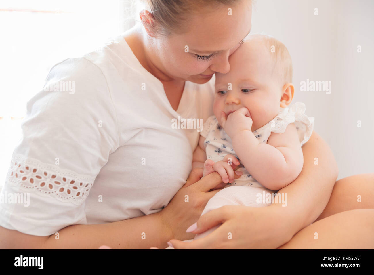 Lächelnde Mutter kümmert sich um ihren wenig traurig baby girl Stockfoto