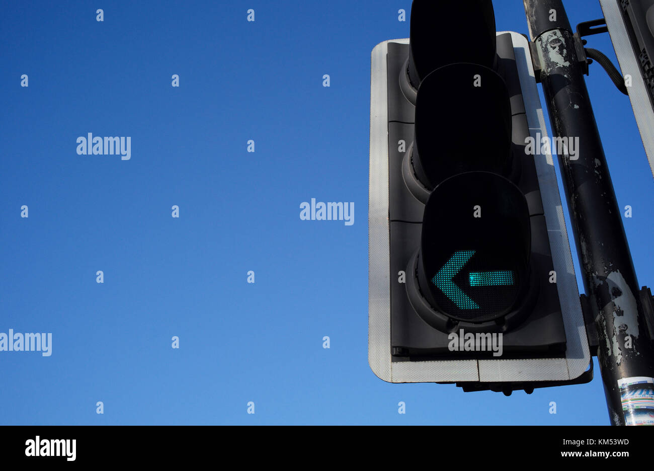 Ampel mit grünem Pfeil Blinker links gegen den blauen Himmel, die für viele visuelle Konzepte verwendet werden können. Stockfoto