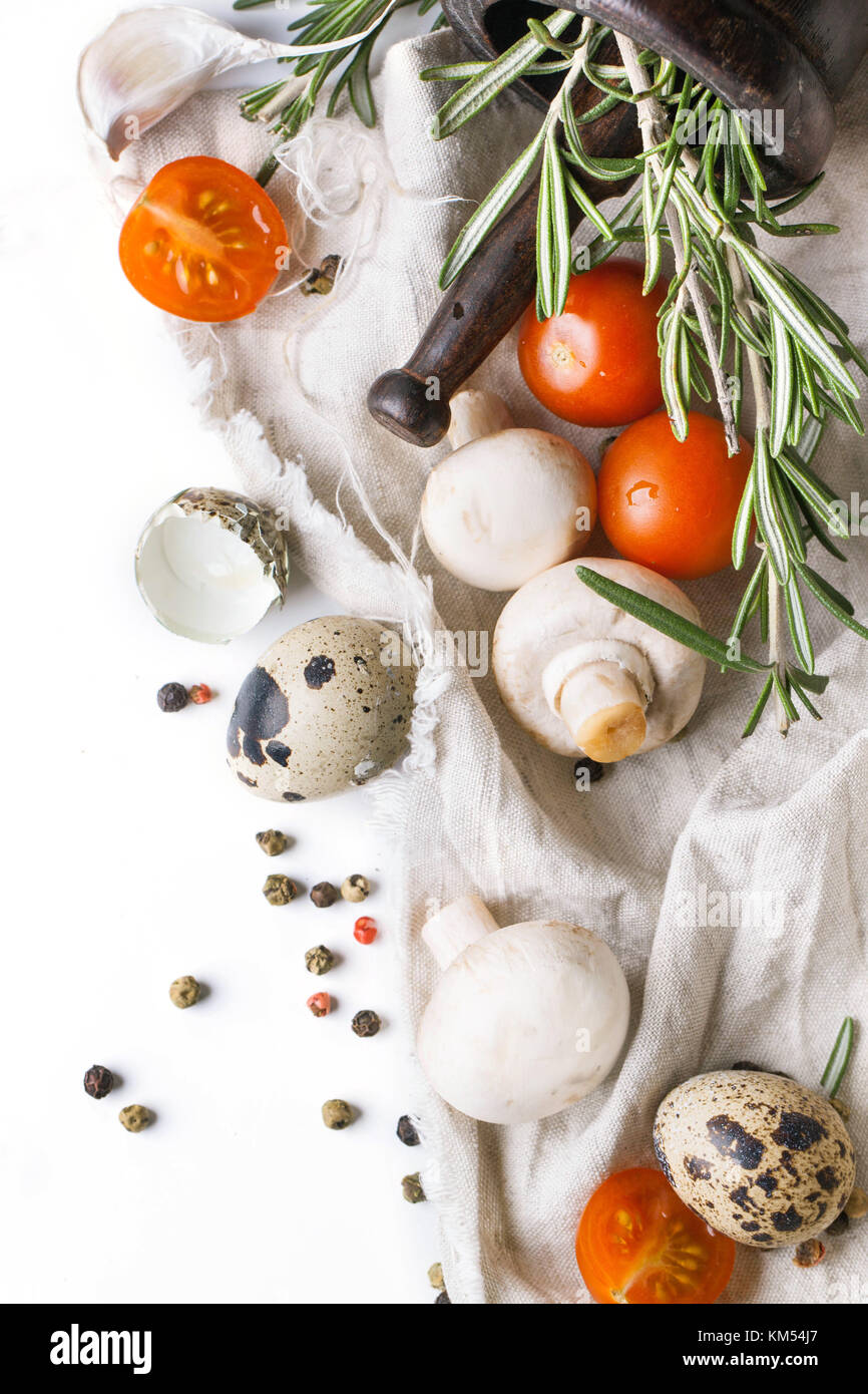 Ansicht von oben auf die wachteleier mit Champignons, in Scheiben geschnittene Tomaten und Rosmarin auf weißer Lappen über Weiß Stockfoto