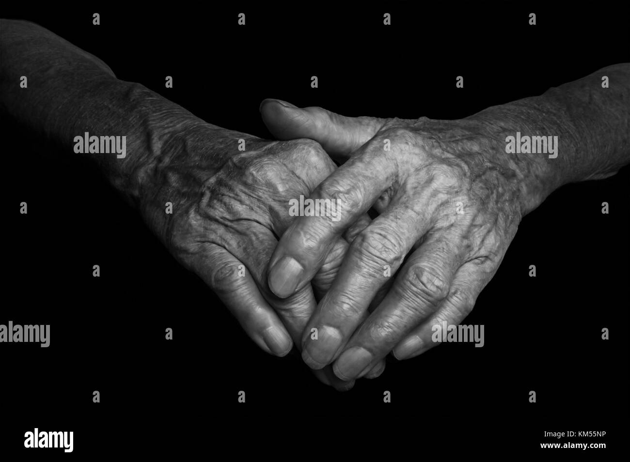 Hände einer alten Frau mit Falten und Falten auf dunklem Hintergrund. Stockfoto