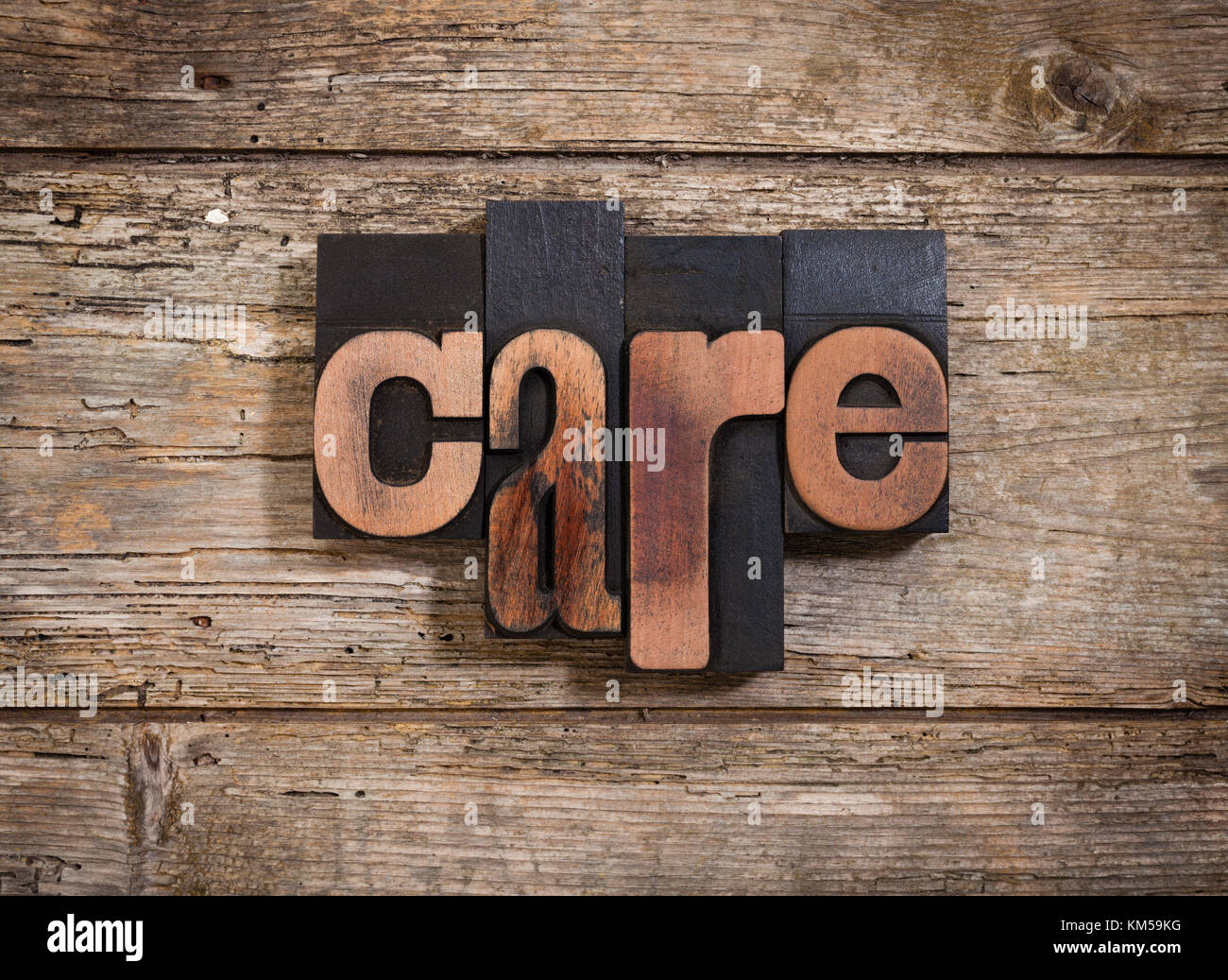 Pflege, einzelnes Wort mit Vintage Buchdruck Blöcke auf rustikalen Holzmöbeln Hintergrund Stockfoto