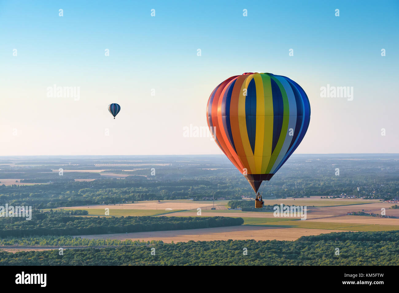Luftaufnahme von bunten Heißluftballons über einem Wald auf abendliche Beleuchtung fliegen Stockfoto