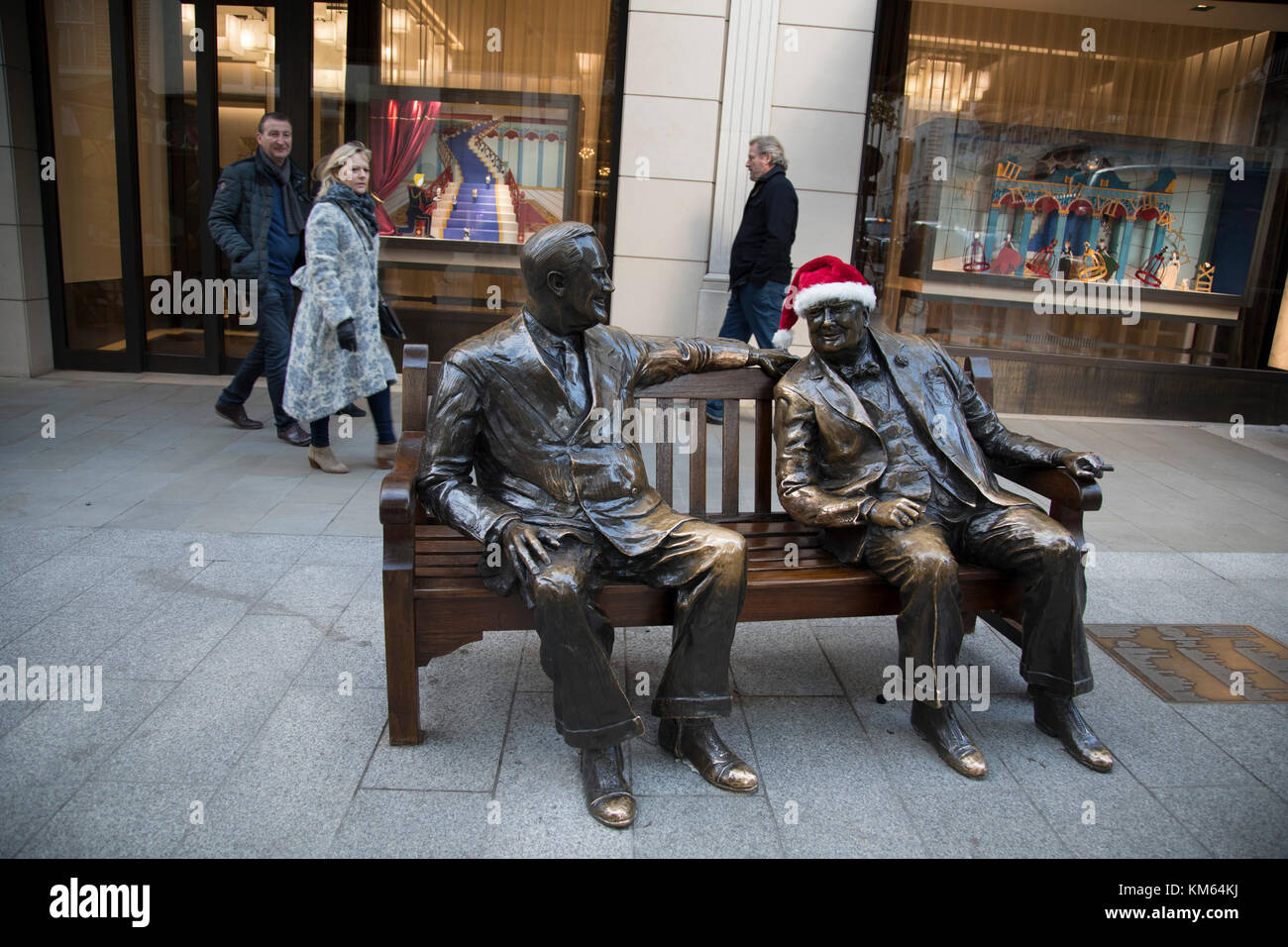 Winston Churchill trägt einen Weihnachtsmütze auf der Statue Alliierte des Bildhauers Lawrence Holofcener von Präsident Roosevelt und Winston Churchill in der Bond Street, einer der exklusivsten Einkaufs- und Modestraßen in London, England, Großbritannien. Stockfoto