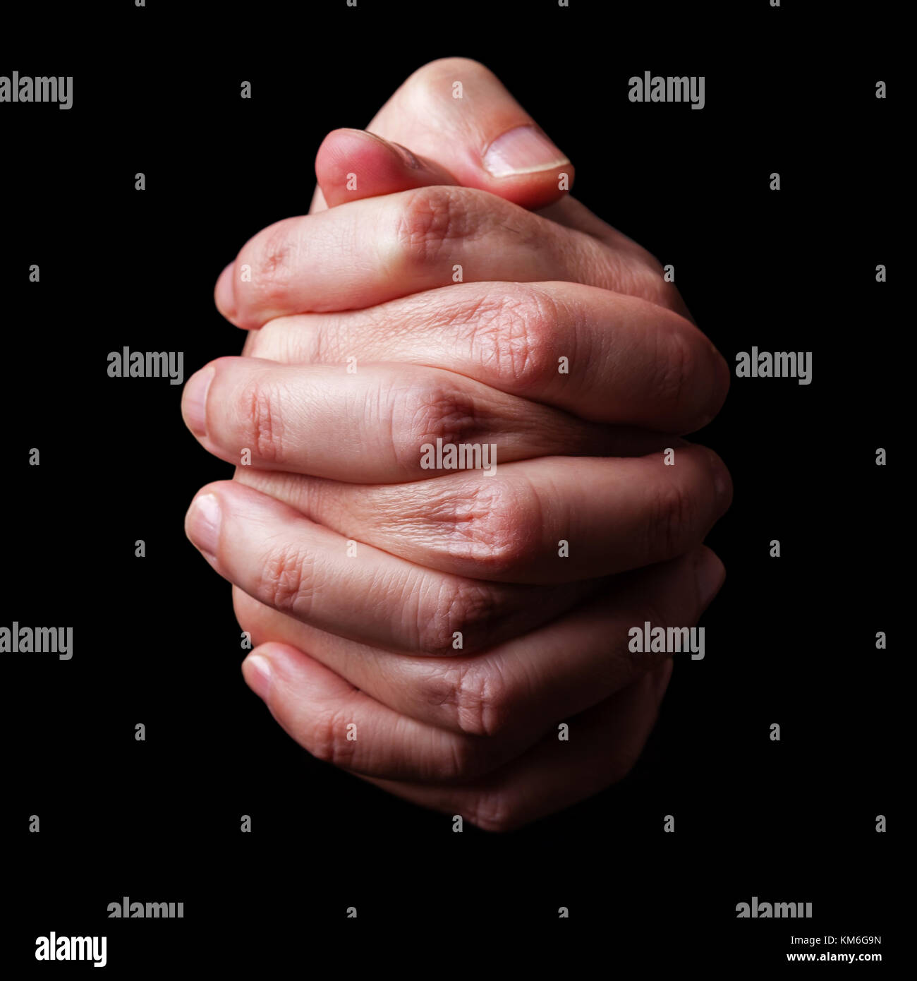 Low Key, in der Nähe der Hände eines treuen reifer Mann, der betet, die Hände gefaltet, interlaced Finger in Anbetung zu Gott. Isolierte schwarze Hintergrund. Die Religion Stockfoto