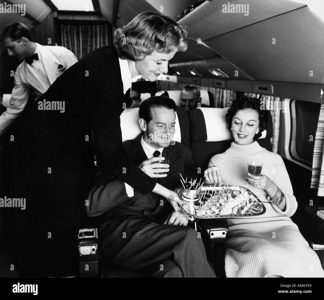Die SAS Convair CV 440 Metropolitan, ein Flugzeug aus der Mitte des Jahrhunderts, ist hier während des Flugbetriebs abgebildet. Eine Airhostess serviert Passagieren Snacks, die den klassischen Flugzeugservice der damaligen Zeit zum Ausdruck bringen. Stockfoto