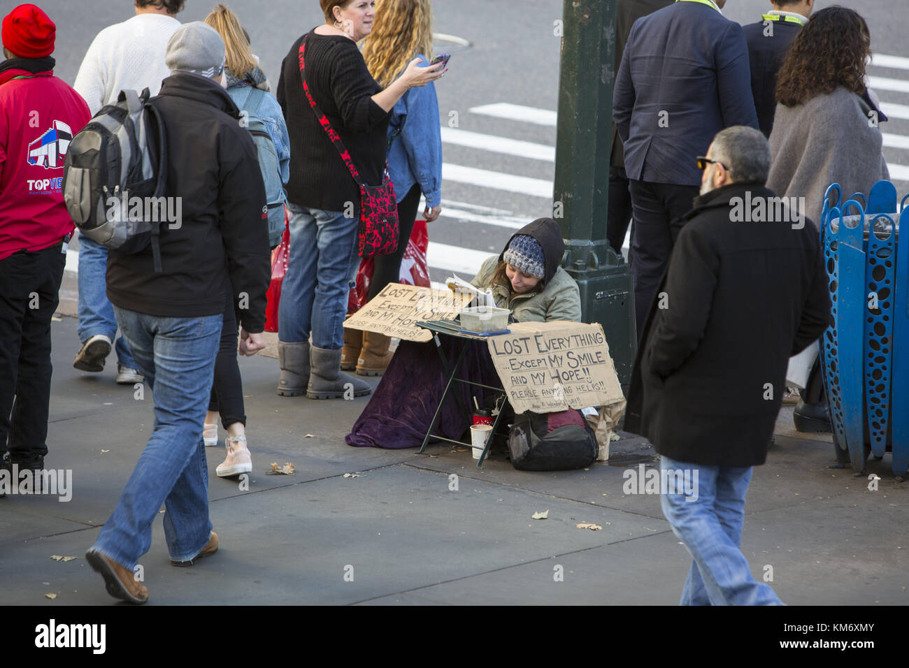 Frau bittet um Geld an der 42. Straße und 5th Avenue mit einem Zeichen, das sagt sie alles verloren, außer ihre Hoffnung und ihr Lächeln hat. New York City. Stockfoto