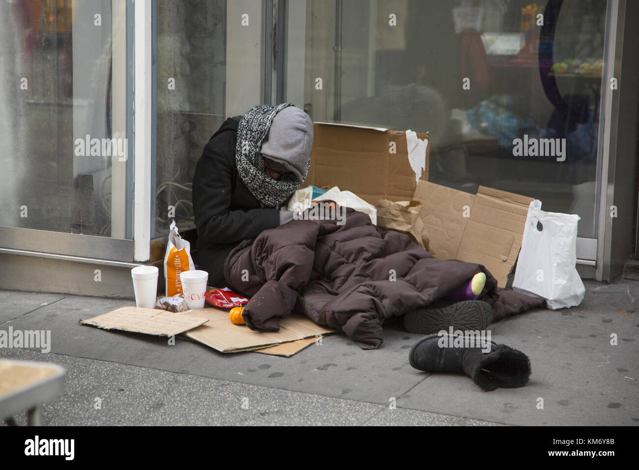 Obdachlose Frau schläft auf dem Bürgersteig außerhalb einer Store aliong Broadway in der Nähe der 34th Street, in Midtown Manhattan, New York City. Stockfoto