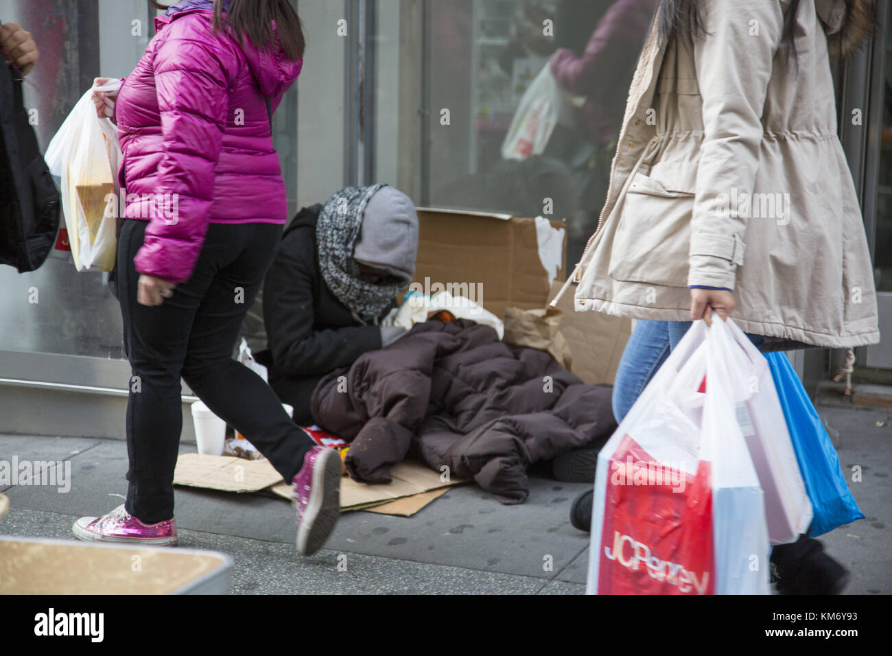 Obdachlose Menschen teilen die Bürgersteige mit feiertagkäufer in Midtown Manhattan am Schwarzen Freitag Thanksgiving Wochenende, dem offiziellen Beginn der Weihnachten Holiday Shopping Season Kennzeichnung. Stockfoto