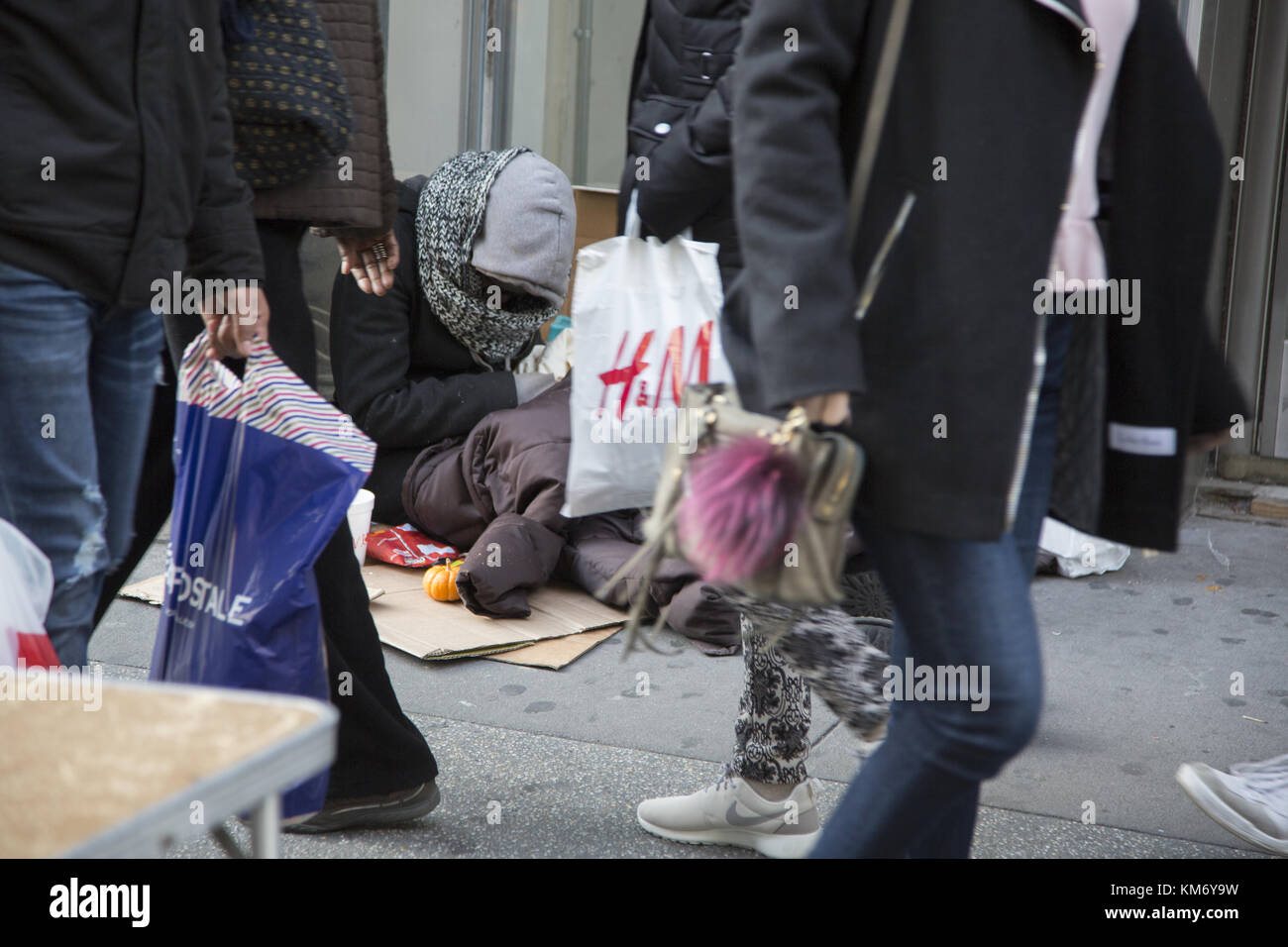 Obdachlose Menschen teilen die Bürgersteige mit feiertagkäufer in Midtown Manhattan am Schwarzen Freitag Thanksgiving Wochenende, dem offiziellen Beginn der Weihnachten Holiday Shopping Season Kennzeichnung. Stockfoto