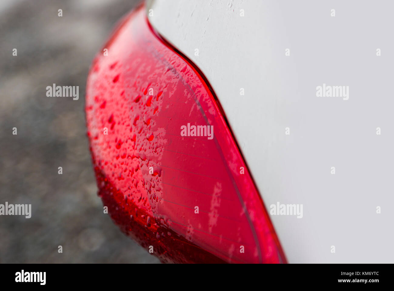 Regentropfen auf einem roten Auto Scheinwerfer Stockfoto