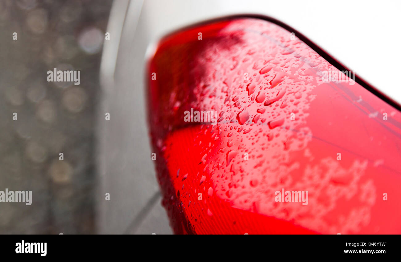 Regentropfen auf einem roten Auto Scheinwerfer Stockfoto