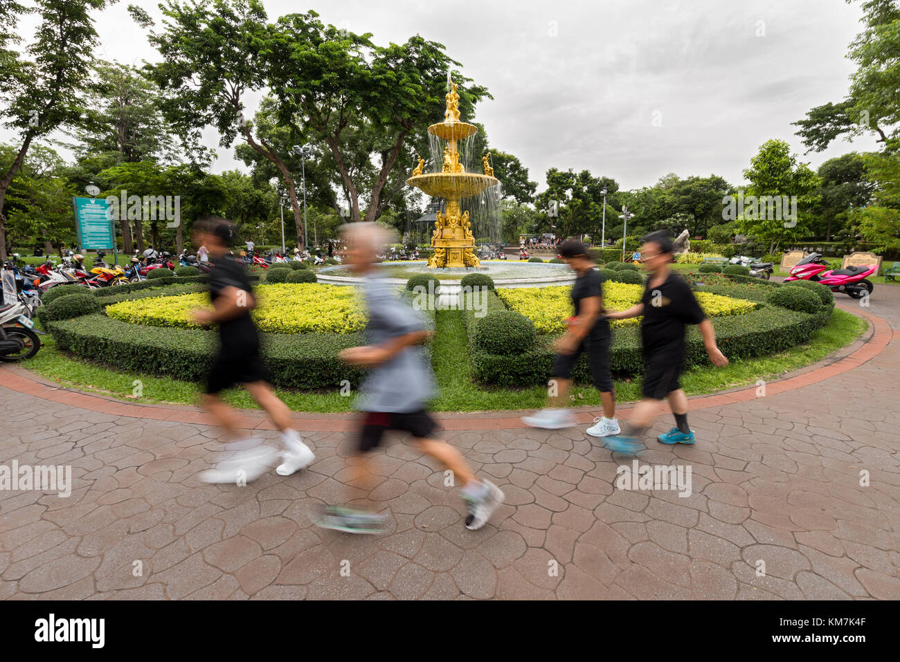 Lokale Thais von Bangkok, die es morgen Übung in einem öffentlichen Park vorbei vor einer großen goldenen Brunnen. Stockfoto