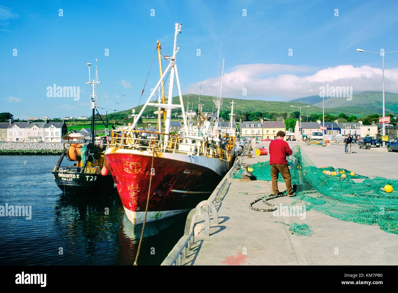 Fischer Flicken Fischernetze neben Angelboote/Fischerboote im Hafen von Dingle auf der Dingle Halbinsel, County Kerry, West-Irland. Stockfoto