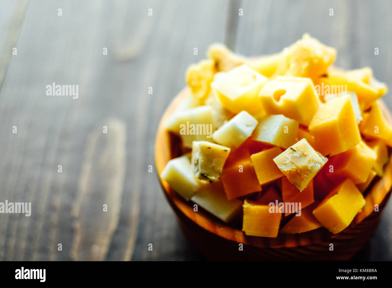 Hölzerne Schüssel mit Stücken von verschiedenen Holland Hartkäse Stockfoto