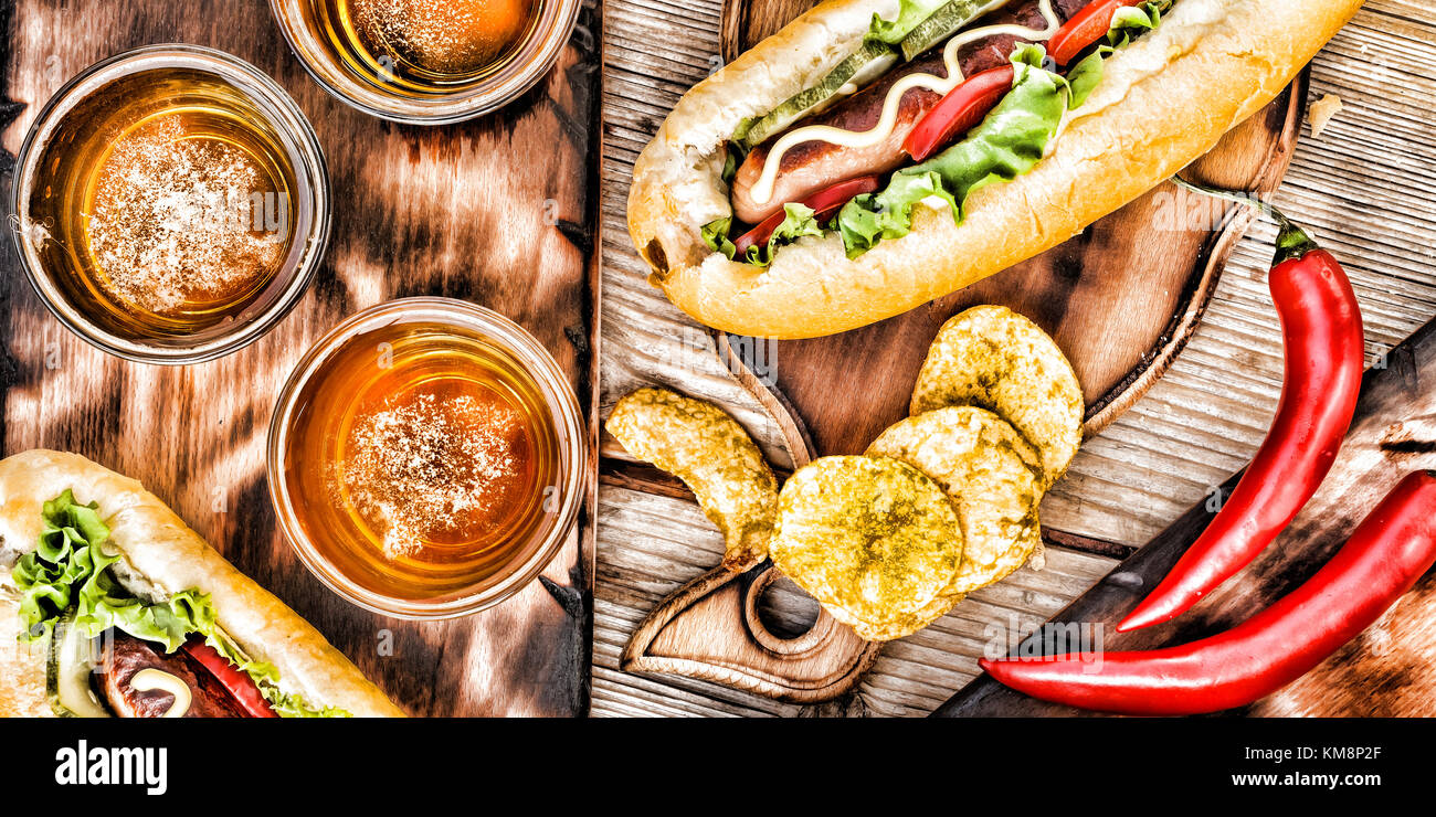 Hot Dogs, Bier, Chips auf hölzernen Tisch in der Kneipe. Stockfoto