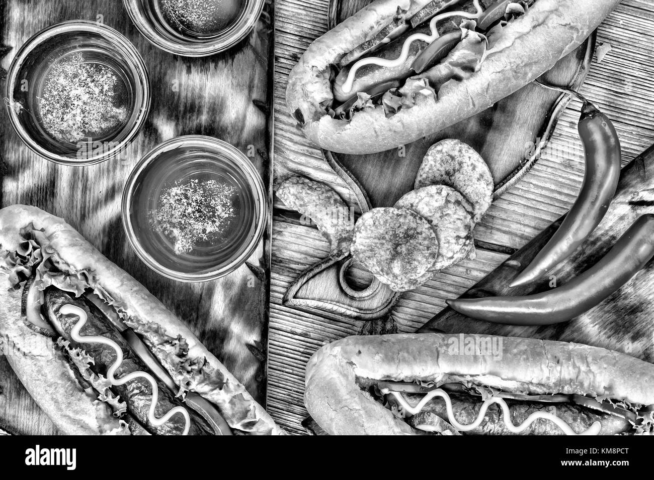 Schwarz-weiß Foto. Hot Dogs, Bier, Chips auf hölzernen Tisch in der Kneipe. Stockfoto