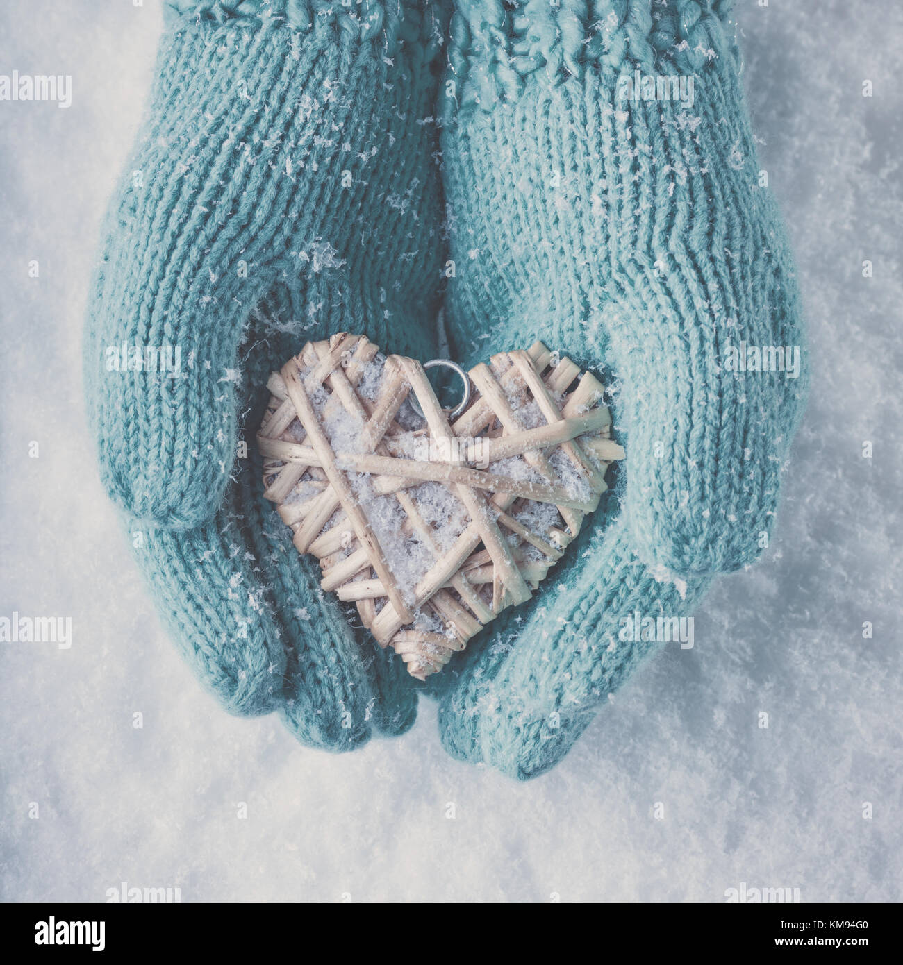 Frau Hände in Light teal Gestrickte Handschuhe halten einen schönen Herzen im Schnee Hintergrund. Liebe und st. Valentin Konzept. instagram Wirkung. Stockfoto