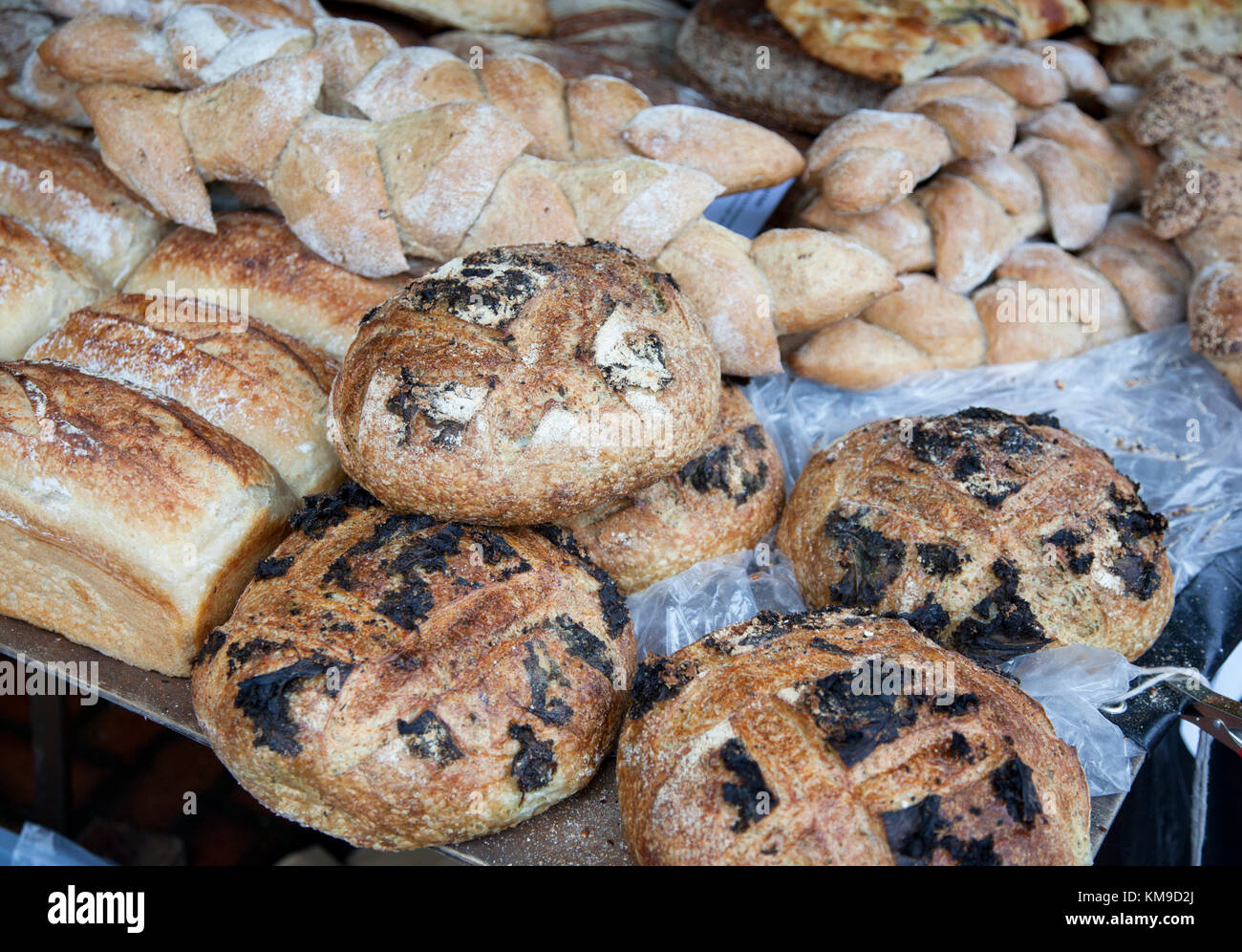 Eine Nahaufnahme ungewöhnlicher Sauerteigbrote aus Grünkohl und Sesamsamen in einem Backstubenstand auf einem Bauernmarkt in Stroud, Gloucestershire, Großbritannien Stockfoto