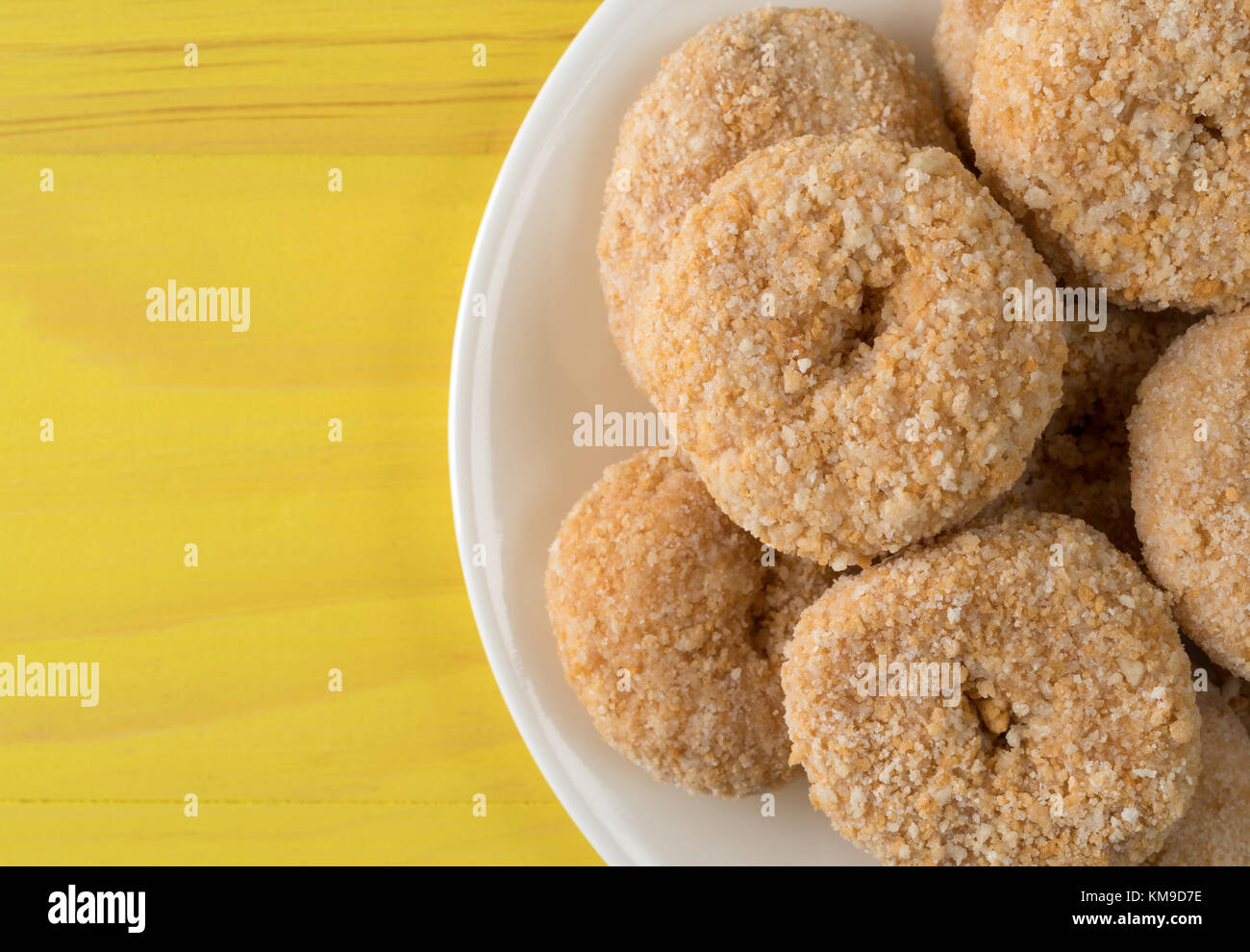 Top Ansicht schließen von Karamell flake Donuts auf eine weisse Platte auf einem hellen gelb lackierten Holz Tisch. Stockfoto