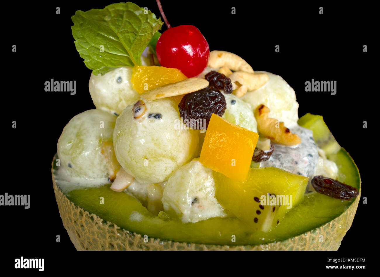 Eis in frischer Melone mit Obstsalat darauf Isoliert auf schwarzem Hintergrund Stockfoto