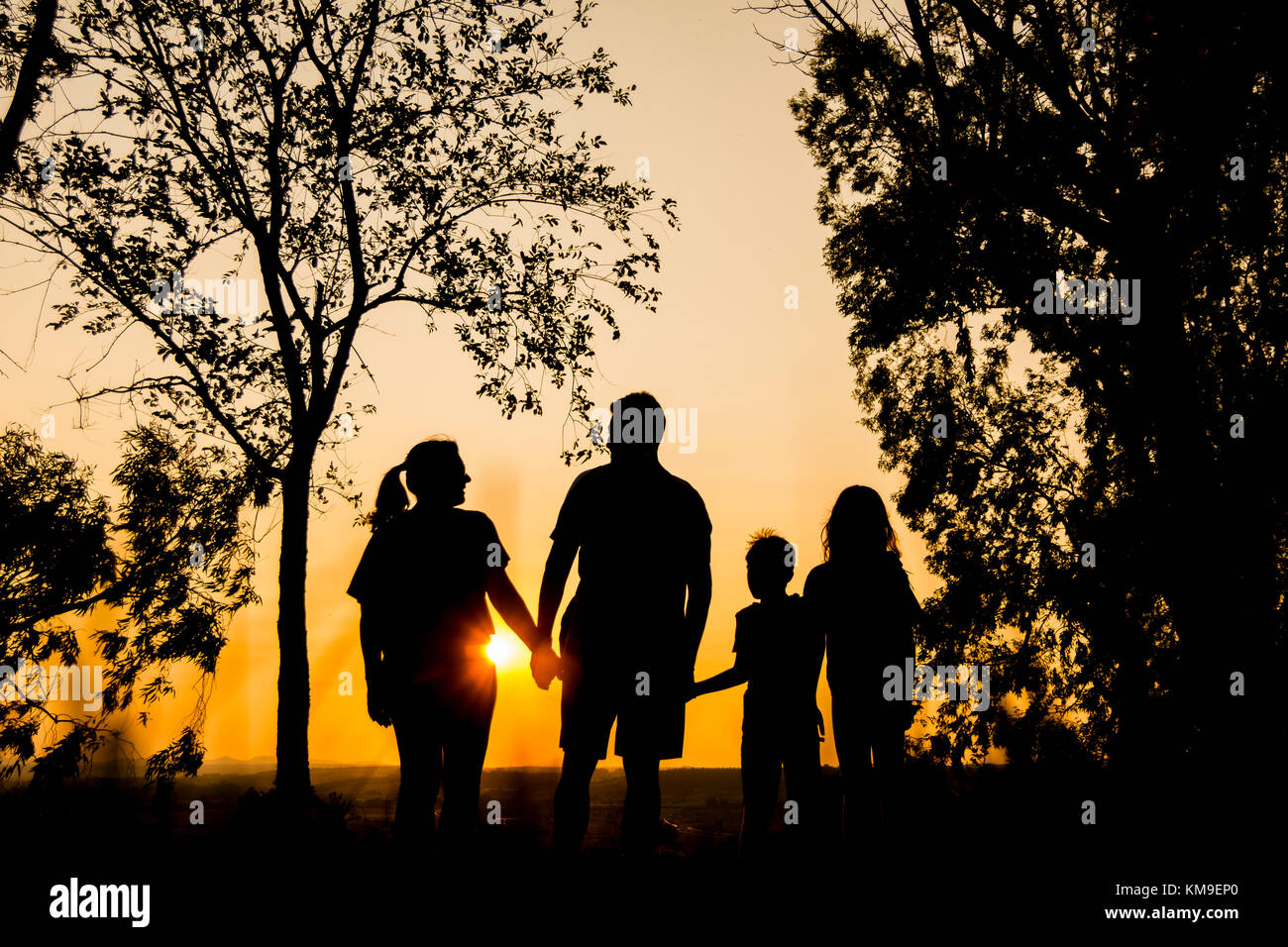Silhouette einer Familie mit zwei Kindern, das Hände bei Sonnenuntergang Stockfoto