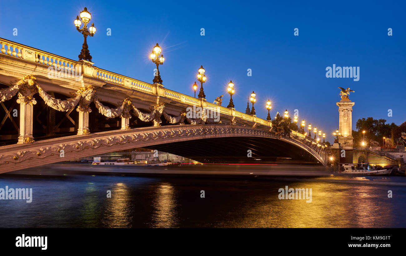 Panoramablick auf die Pont Alexandre III Brücke beleuchtet am Abend mit dem Fluss Seine. 8. Arrondissement, Paris, Frankreich Stockfoto