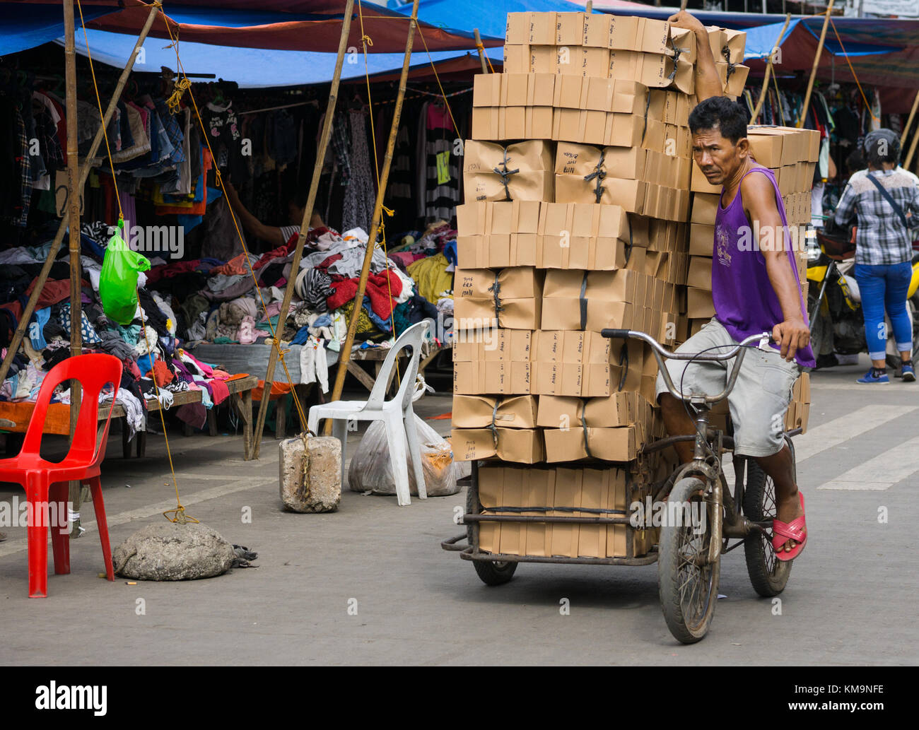 Ein Mann balanciert eine große Ladung Pappkartons, die auf einem Trisikad, Carbon Market, Cebu City, Philippinen gestapelt sind Stockfoto