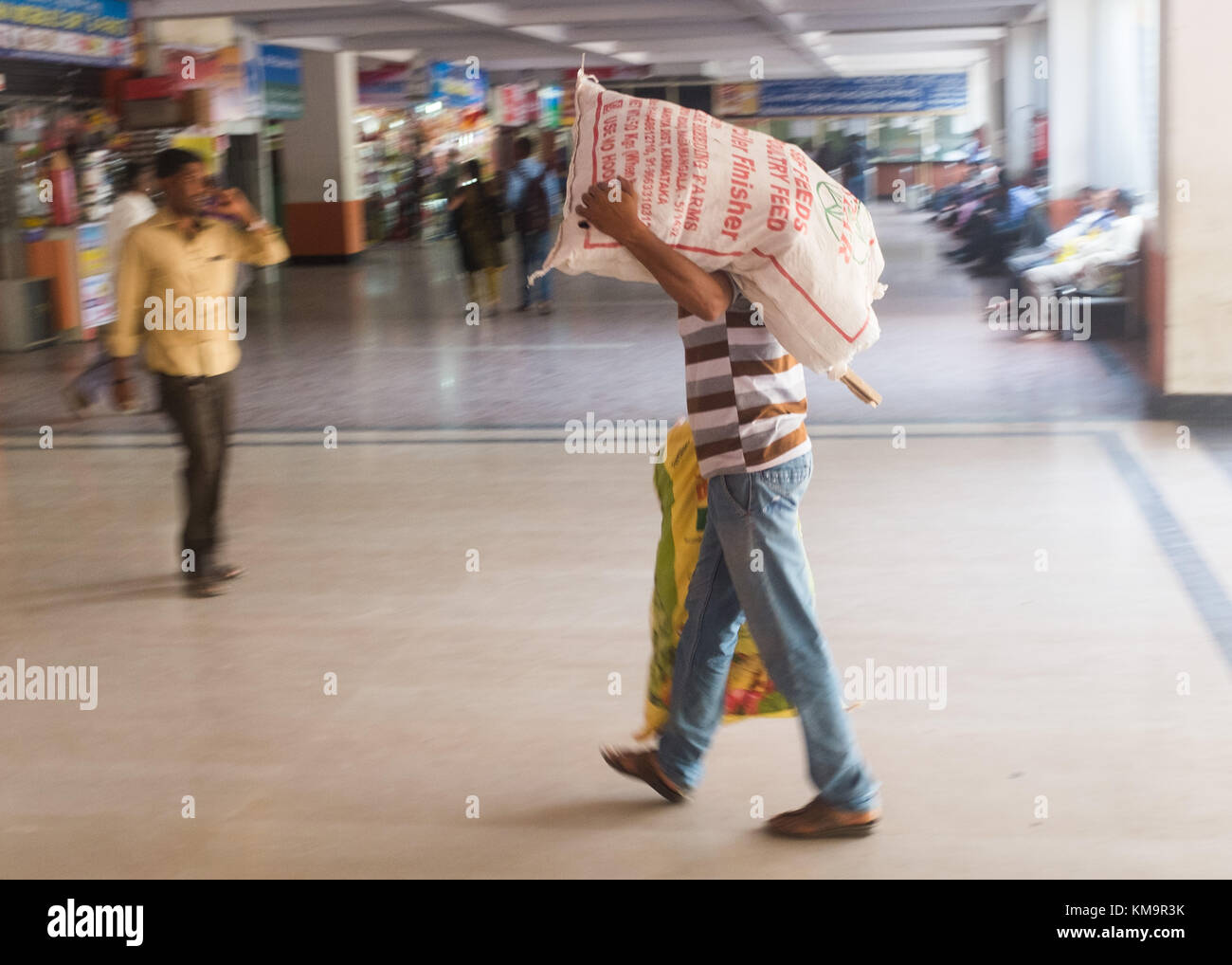 Mann Tragen von schweren Sack in Bus Station, Mysore, Karnataka, Indien. Stockfoto