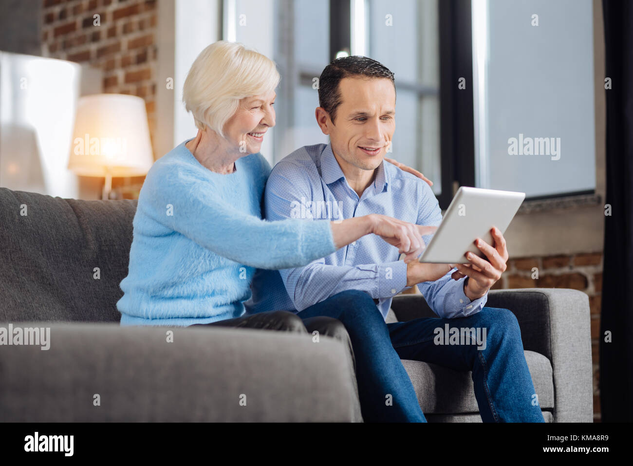 Lebendige ältere Frau und ihr Sohn tun Online shopping Stockfoto