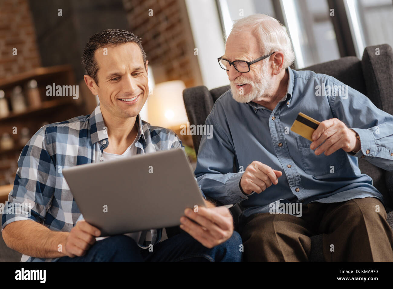 Junger Mann und seinen alten Vater tun Online shopping zusammen Stockfoto